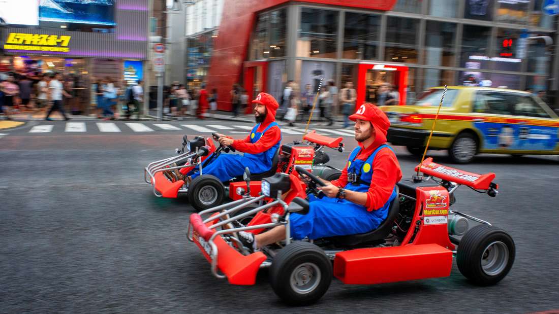 Two people in Super Mario costumes drive through Tokyo 